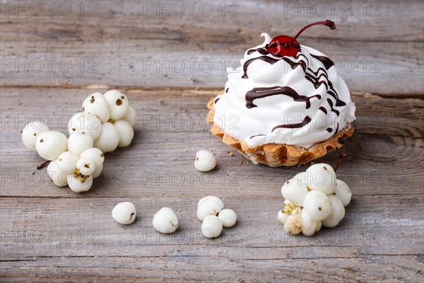 A cake with cream and white berries on a rustic wooden background