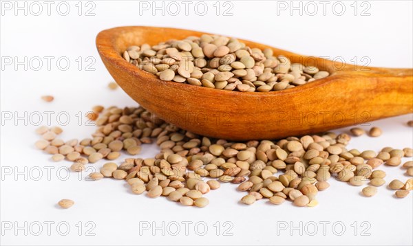 Pile of green lentils in a wooden spoon isolated on white background. Closeup