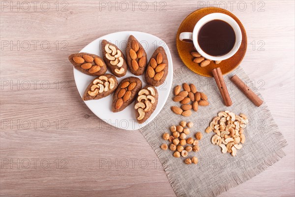 Small cakes potatoes with almonds and cashew nuts on a dessert plate. A cup of coffee, cinnamon, almonds, hazelnuts, cashew on a linen napkin. Still life. Copy space