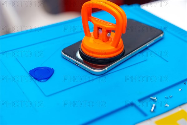 Close-up photo of a suction cup pressing the screen of a mobile to attach it in the desk of a workshop