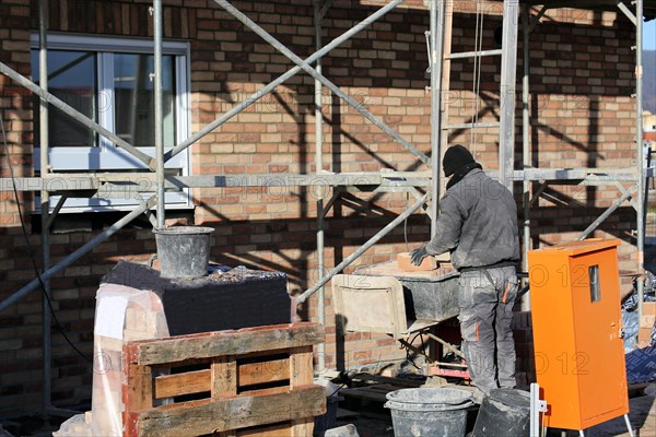 Bricklaying, clinker brick work. Bricklayers clad the facade of a detached house with clinker bricks