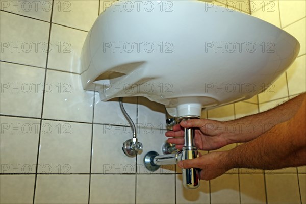 Plumber installs the siphon on a washbasin