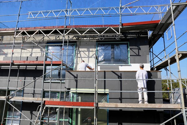 Construction workers insulate a house facade