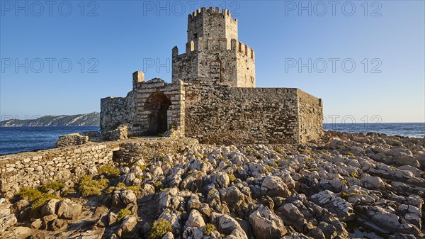 Old ruined fortress with tower-like structure against a clear blue sky next to the sea, octagonal medieval tower. Islet of Bourtzi, sea fortress of Methoni, Peloponnese, Greece, Europe