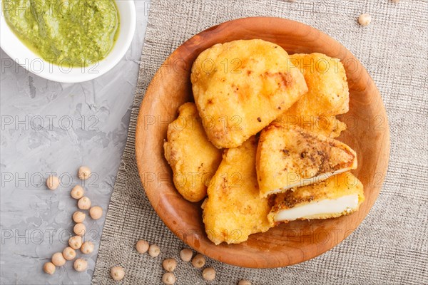 Traditional indian food paneer pakora in wooden plate with mint chutney on a gray concrete background. top view, flat lay