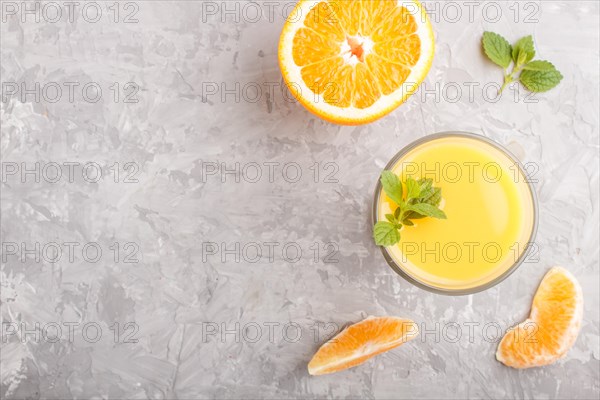 Glass of orange juice on a gray concrete background. Morninig, spring, healthy drink concept. Top view, copy space, flat lay