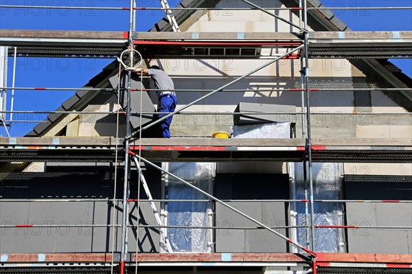 Construction workers insulate a house facade