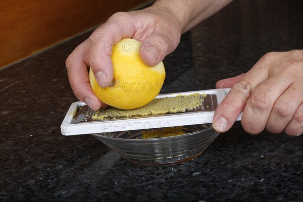 Preparation lemon sauce for fillet of Dreisam salmon with wild rice, grating lemon peel, kitchen grater, grater, men's hands, glass bowl, southern German cuisine, lemon sauce, salmon fillet, healthy eating, food, studio, fish dish, cooking, Germany, Europe