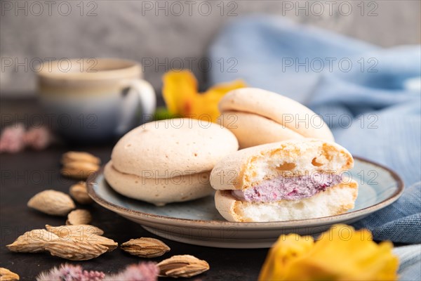 Meringues cakes with cup of coffee on a black concrete background and blue linen textile. Side view, close up, selective focus