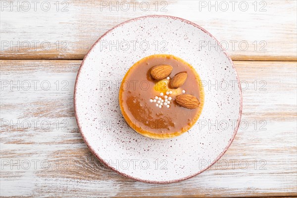 Sweet tartlets with almonds and caramel cream on a white wooden background. top view, flat lay, close up