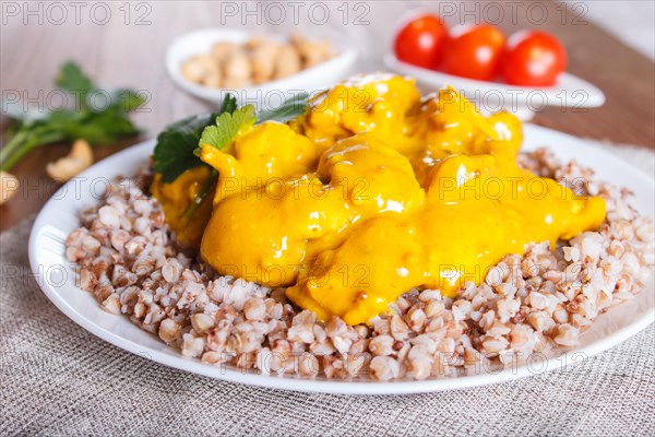 Buckwheat with chicken curry sauce with cashew on brown wooden background. close up, selective focus