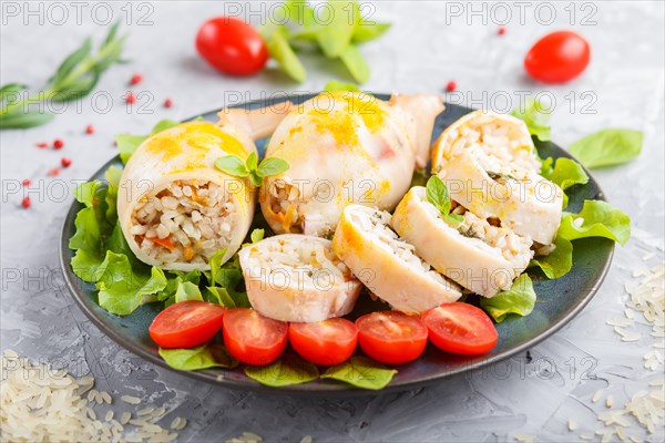 Stuffed baked squid with greens on a blue ceramic plate on a gray concrete background, side view, close up, selective focus