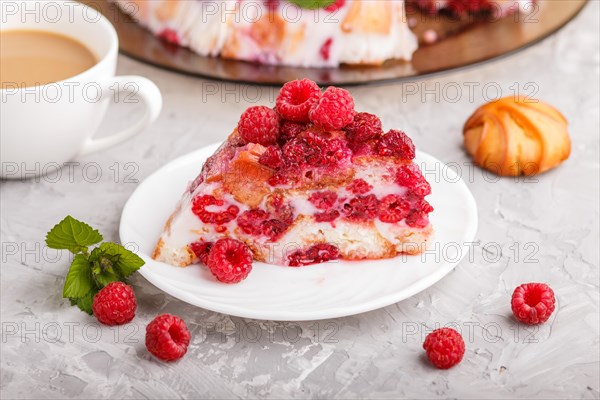 Homemade jelly cake with milk, cookies and raspberry on a gray concrete background with cup of coffee. side view. close up