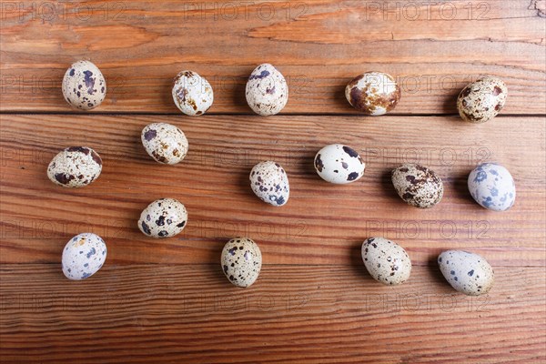 Raw quail eggs on a brown wooden background. top view