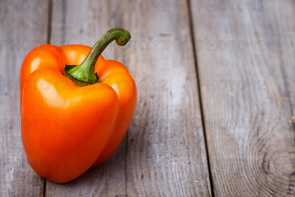 Fresh orange pepper on a rustic wooden background