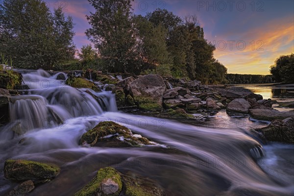 A waterfall in the evening light on the Old Rhine near Speyer as a long exposure