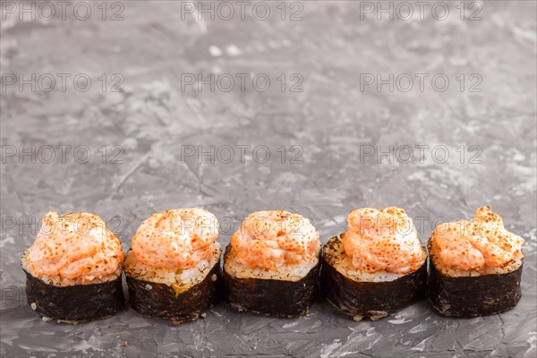 Japanese maki sushi rolls with flying fish roe, cheese on black concrete background. Side view, close up, copy space