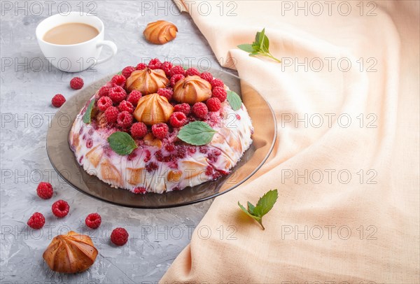Homemade jelly cake with milk, cookies and raspberry on a gray concrete background with cup of coffee and orange textile. side view. copy space