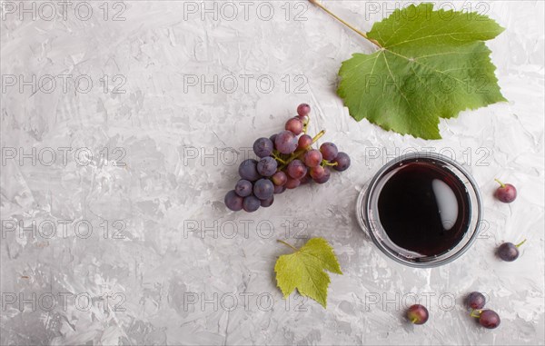 Glass of red grape juice on a gray concrete background. Morninig, spring, healthy drink concept. Top view, copy space, flat lay