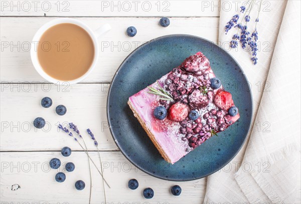 Berry cake with milk cream and blueberry jam on blue ceramic plate with cup of coffee and fresh blueberries on a white wooden background. top view, flat lay, close up