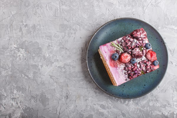 Berry cake with milk cream and blueberry jam on blue ceramic plate on a gray concrete background. top view, flat lay, copy space