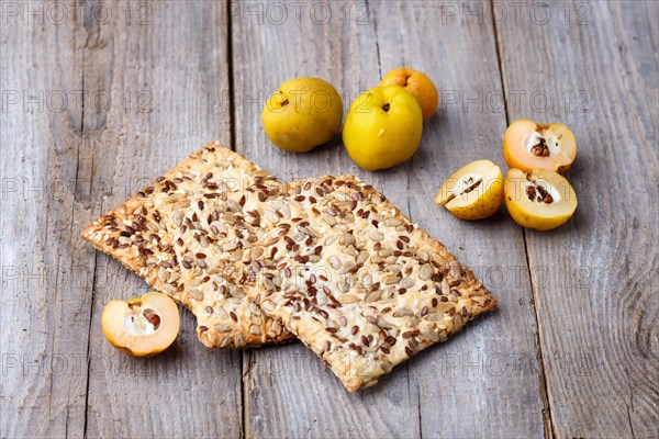 Biscuits with flax, sesame and sunflower seeds and yellow quince fruit on a rustic wooden background