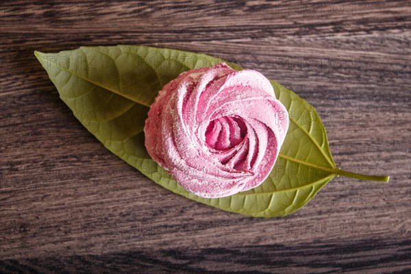 Single pink homemade marshmallows on a gray wooden background. top view