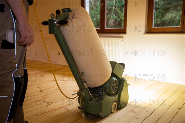 Craftsmen professionally sanding a plank floor