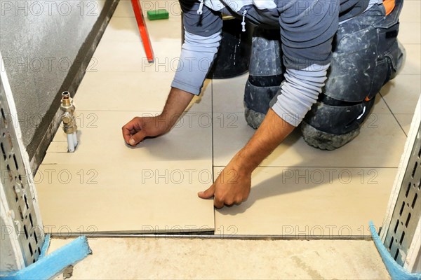 Tiler lays modern large floor tiles in a bathroom