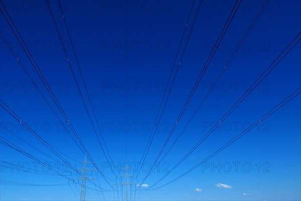 High-voltage lines with pylons against a blue sky