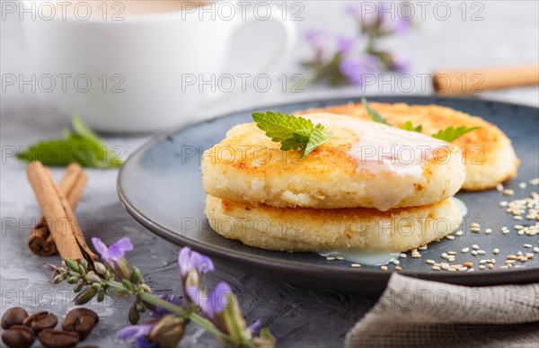 Cheese pancakes on a blue ceramic plate and a cup of coffee on a gray concrete background. side view, close up