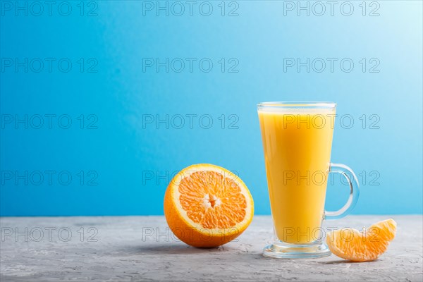 Glass of orange juice on a gray and blue background. Morninig, spring, healthy drink concept. Side view, copy space