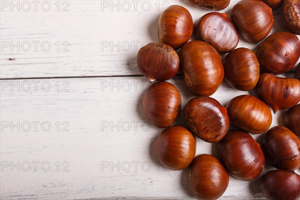 Pile of sweet chestnuts on white wooden background with copy space, top view