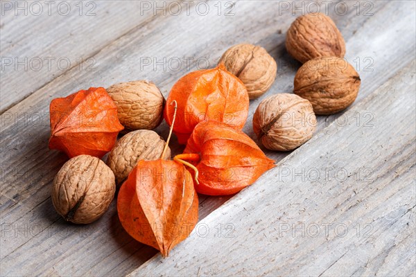 Walnuts and red physalis on rustic wooden background with copy space