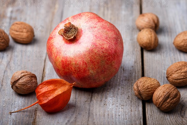 Ripe garnet with walnuts on a rustic wooden background