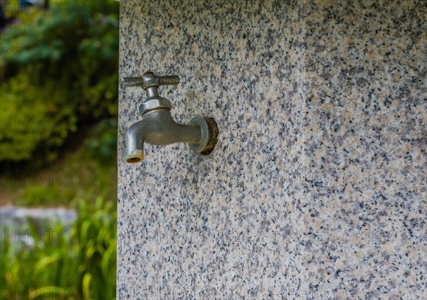 Closeup of water faucet on marble water fountain in public park in South Korea