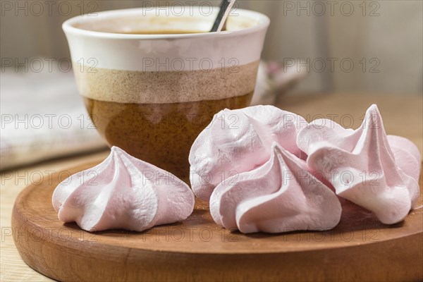 Chewing marshmallows, meringue and coffee cup on a wooden board and linen tablecloth