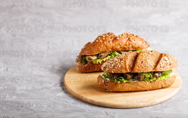 Sprats sandwiches with lettuce and cream cheese on wooden board on a gray concrete background. side view, copy space, selective focus