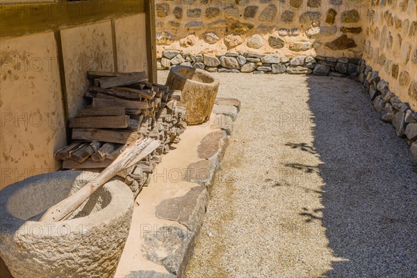 Chopped word and stone grinding pot next to wall of traditional house located in public park at Neungsa Baekje Temple in South Korea