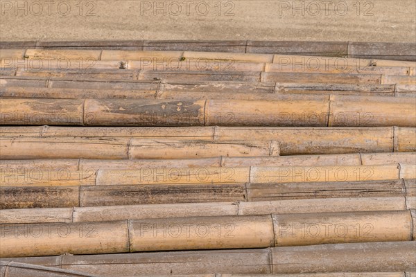 Closeup of weathered cracked bamboo poles laying on concrete in South Korea