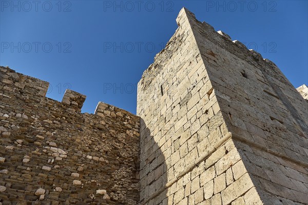 The sunlit wall of an old castle rises into the deep blue sky, sea fortress Methoni, Peloponnese, Greece, Europe