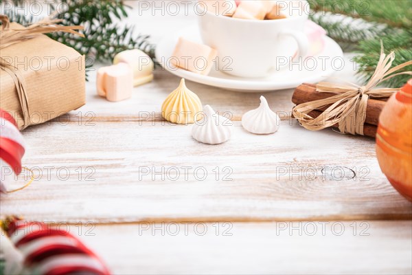 Christmas or New Year composition. Decorations, box, balls, cinnamon, fir and spruce branches, cup of coffee, on a white wooden background. Side view, copy space, selective focus
