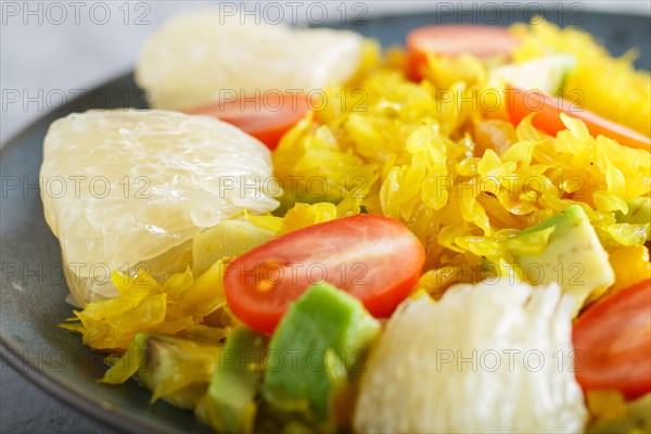 Fried pomelo with tomatoes and avocado on gray concrete background. side view, close up, selective focus, myanmar food