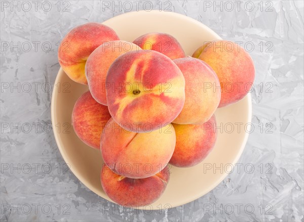 Fresh peaches on a plate on gray concrete background. top view, flat lay, close up