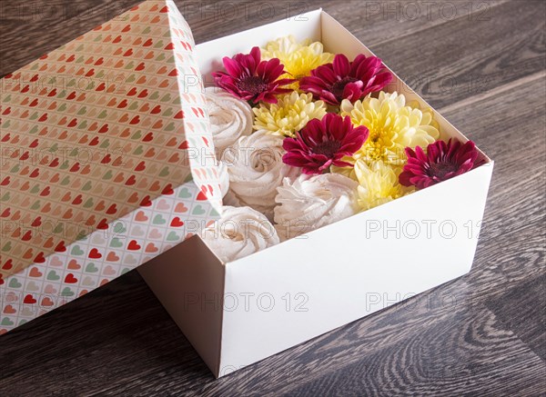 White box with white homemade zephyr and sunflowers and chrysanthemums on gray wooden background