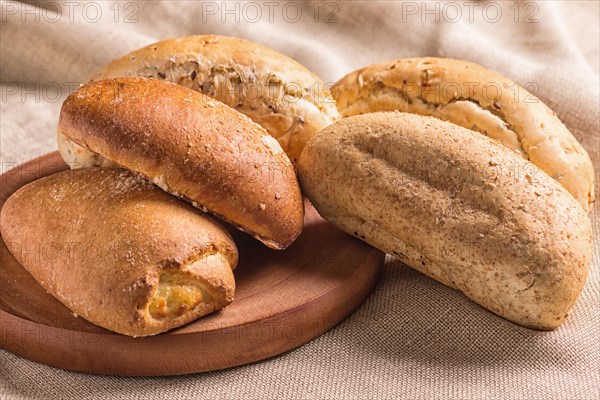 Sweet buns on a wooden board and linen tablecloth