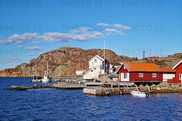 Colourful fishermen's huts nestled against high rocks, small fishing boat, autumn, Vaestra Goetalands Laen, Sweden, Europe