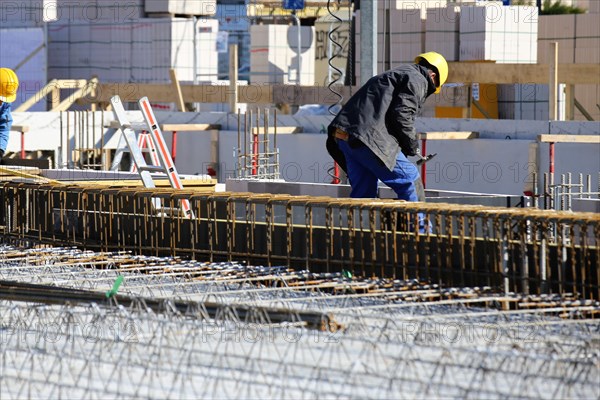 Construction work on the foundations of a large apartment building. The construction workers are wearing construction helmets in accordance with regulations
