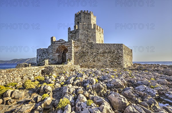 Sunlit castle ruins on a rocky cliff above the sea, octagonal medieval tower. Islet of Bourtzi, sea fortress of Methoni, Peloponnese, Greece, Europe