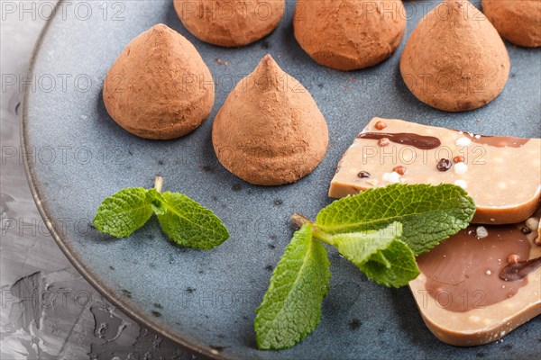 Chocolate truffle on blue ceramic plate on gray concrete background. close up, side view